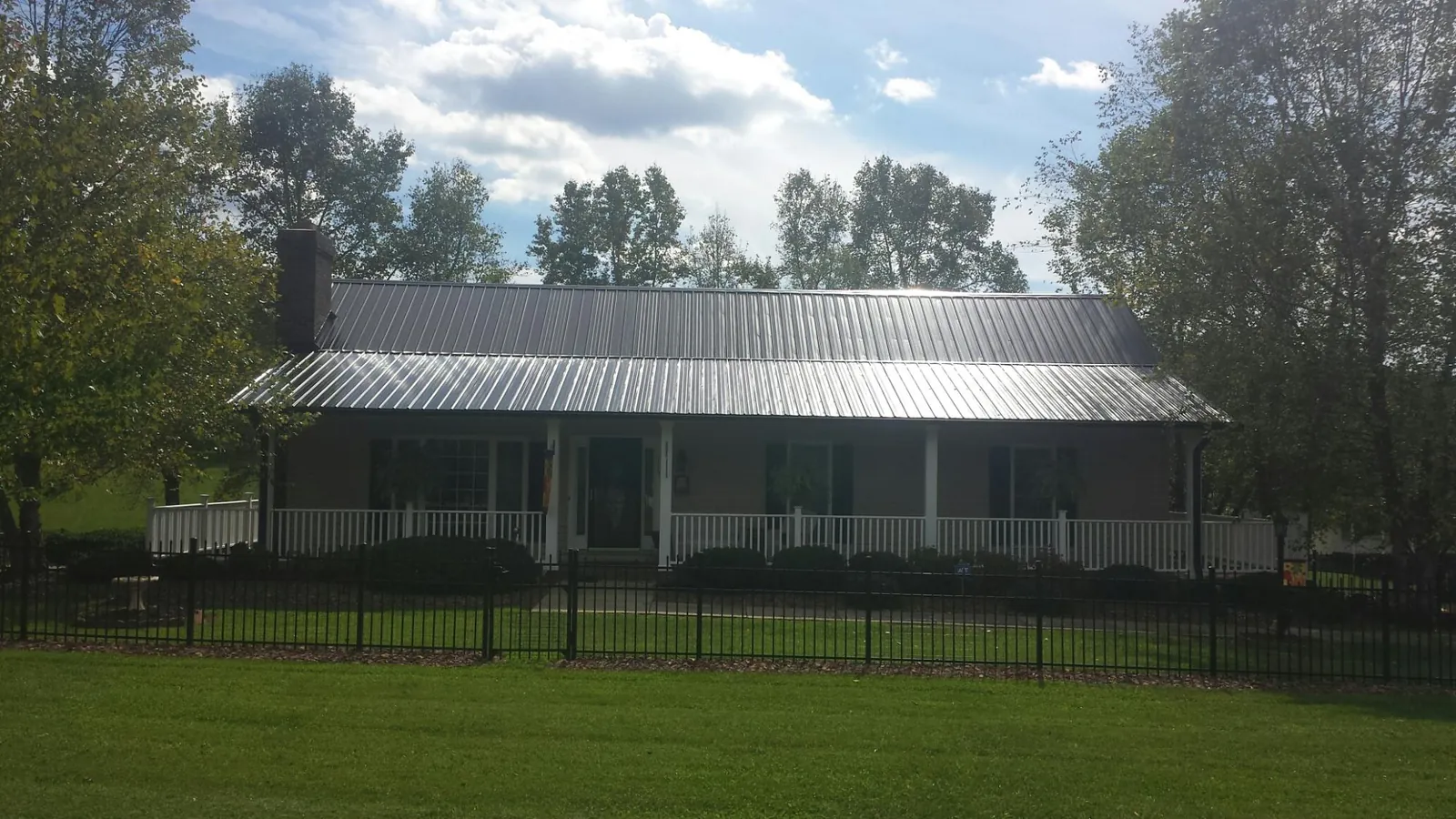 Gray metal roof on a brick ranch with a full width front porch — Gutter Guard Installation work by our crew in Cottage Grove